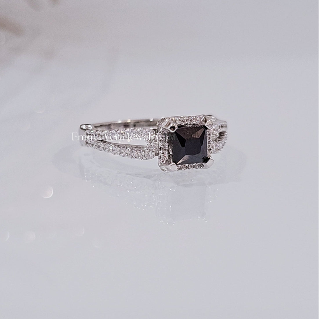 This image features an elegant sterling silver ring with a princess cut sapphire centerpiece. The ring's design is modern, showcasing a sleek, square cut with pointed corners and brilliant facets that enhance its exceptional sparkle.