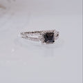 This image features an elegant sterling silver ring with a princess cut sapphire centerpiece. The ring's design is modern, showcasing a sleek, square cut with pointed corners and brilliant facets that enhance its exceptional sparkle.